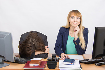 Image showing  The situation in office - frustrated woman lay on the table, her colleague happily looks into the frame