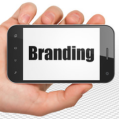 Image showing Marketing concept: Hand Holding Smartphone with Branding on display