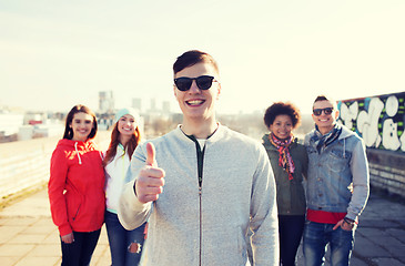 Image showing happy teenage friends showing thumbs up on street