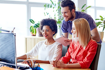 Image showing happy creative team with computer in office