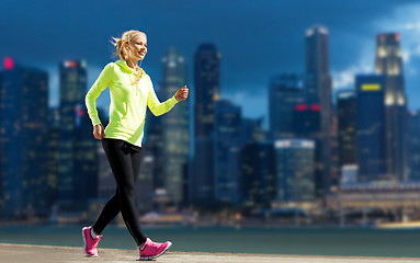 Image showing happy woman jogging over city street background