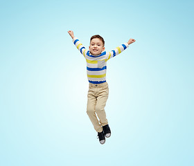 Image showing happy little boy jumping in air over blue