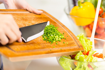 Image showing close up of woman with chopped onion cooking salad