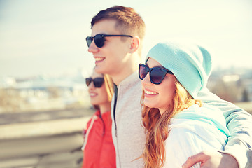 Image showing happy teenage friends in shades hugging on street