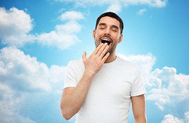 Image showing yawning man over blue sky background