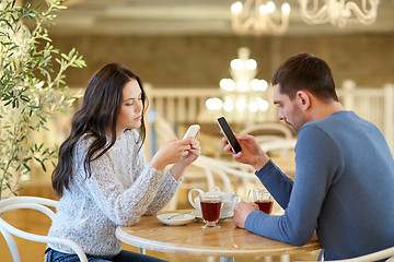 Image showing couple with smartphones drinking tea at cafe