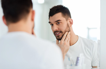 Image showing happy young man looking to mirror at home bathroom