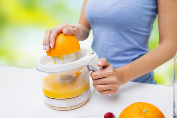 Image showing close up of woman squeezing orange juice at home