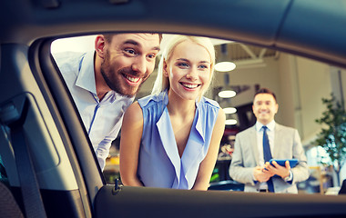 Image showing happy couple with car dealer in auto show or salon