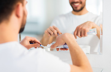 Image showing close up of man squeezing toothpaste on toothbrush