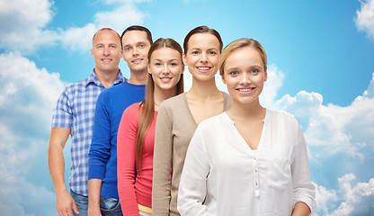 Image showing group of smiling people over blue sky and clouds