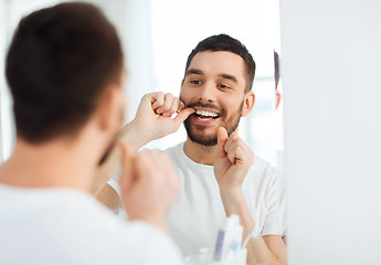 Image showing man with dental floss cleaning teeth at bathroom