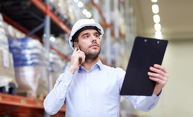 Image showing man with clipboard and smartphone at warehouse