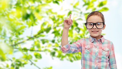 Image showing happy little girl in eyeglasses pointing finger up