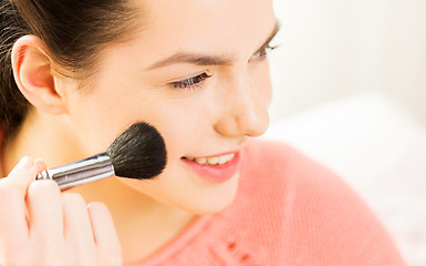 Image showing happy woman with makeup brush blushing cheekbone