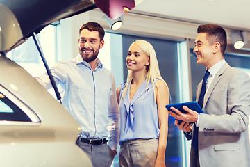 Image showing happy couple with car dealer in auto show or salon