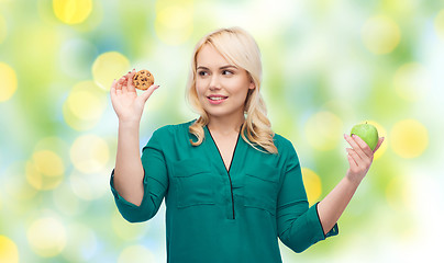 Image showing smiling woman choosing between apple and cookie