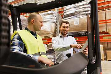 Image showing happy men with tablet pc and forklift at warehouse