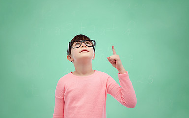 Image showing happy little girl in eyeglasses pointing finger up