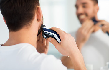 Image showing close up of man shaving beard with trimmer