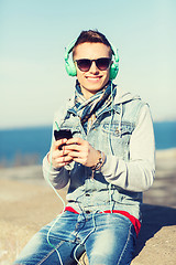 Image showing happy young man in headphones with smartphone