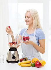 Image showing smiling woman with blender preparing shake at home