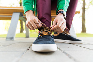 Image showing close up of male hands tying shoe laces on street