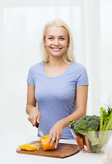 Image showing smiling young woman chopping vegetables at home