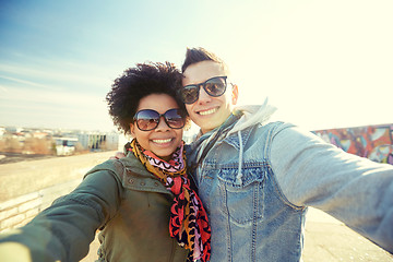 Image showing happy teenage couple taking selfie on city street