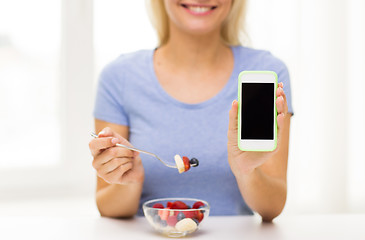 Image showing close up of woman with smartphone eating salad