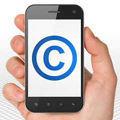 Image showing Law concept: Hand Holding Smartphone with Copyright on display