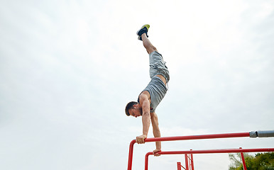 Image showing young man exercising on parallel bars outdoors