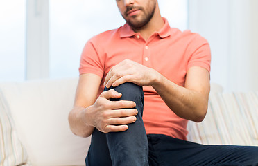 Image showing close up of man suffering from pain in leg at home