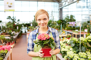 Image showing happy woman holding flowers in greenhouse or shop