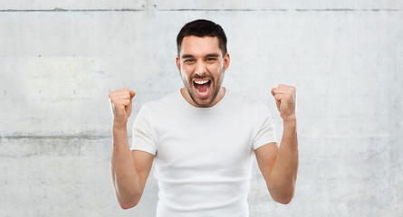 Image showing young man celebrating victory over gray