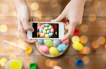 Image showing close up of hands with easter eggs and smartphone