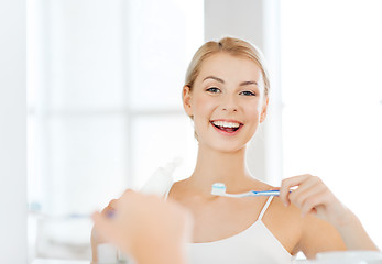 Image showing woman with toothbrush cleaning teeth at bathroom