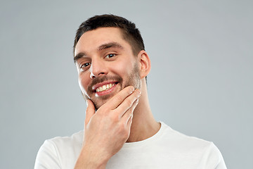 Image showing happy young man touching his face or beard