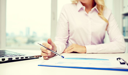 Image showing smiling businesswoman reading papers in office