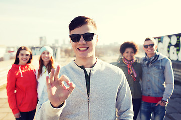 Image showing happy teenage friends showing ok sign on street