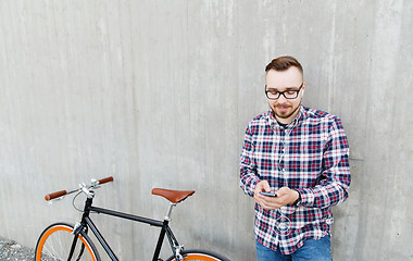 Image showing hipster man in earphones with smartphone and bike