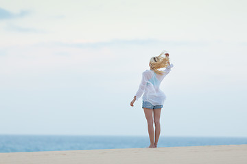 Image showing Woman on sandy beach in white shirt in morning. 