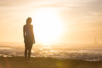 Image showing Woman on sandy beach watching sunset.