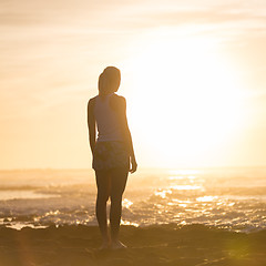 Image showing Woman on sandy beach watching sunset.