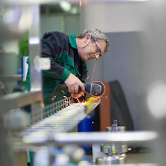 Image showing Industrial worker grinding in manufacturing plant.