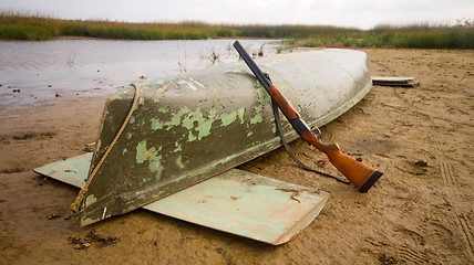 Image showing main equipment of undemanding ducks hunter - canoe and shotgun