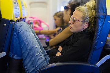 Image showing Tired lady napping on airplane.