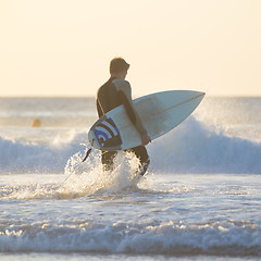 Image showing Silhouette of surfer on beach with surfboard.