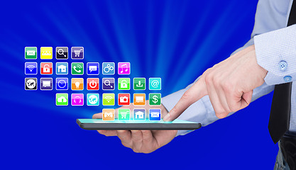 Image showing Businessman holding a tablet pc with mobile applications icons on virtual screen . Internet and business concept.