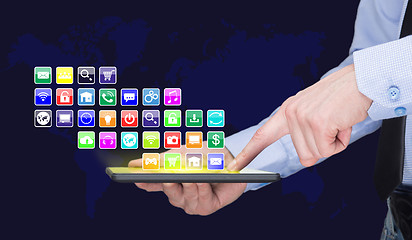 Image showing Businessman holding a tablet pc with mobile applications icons on virtual screen . Internet and business concept.